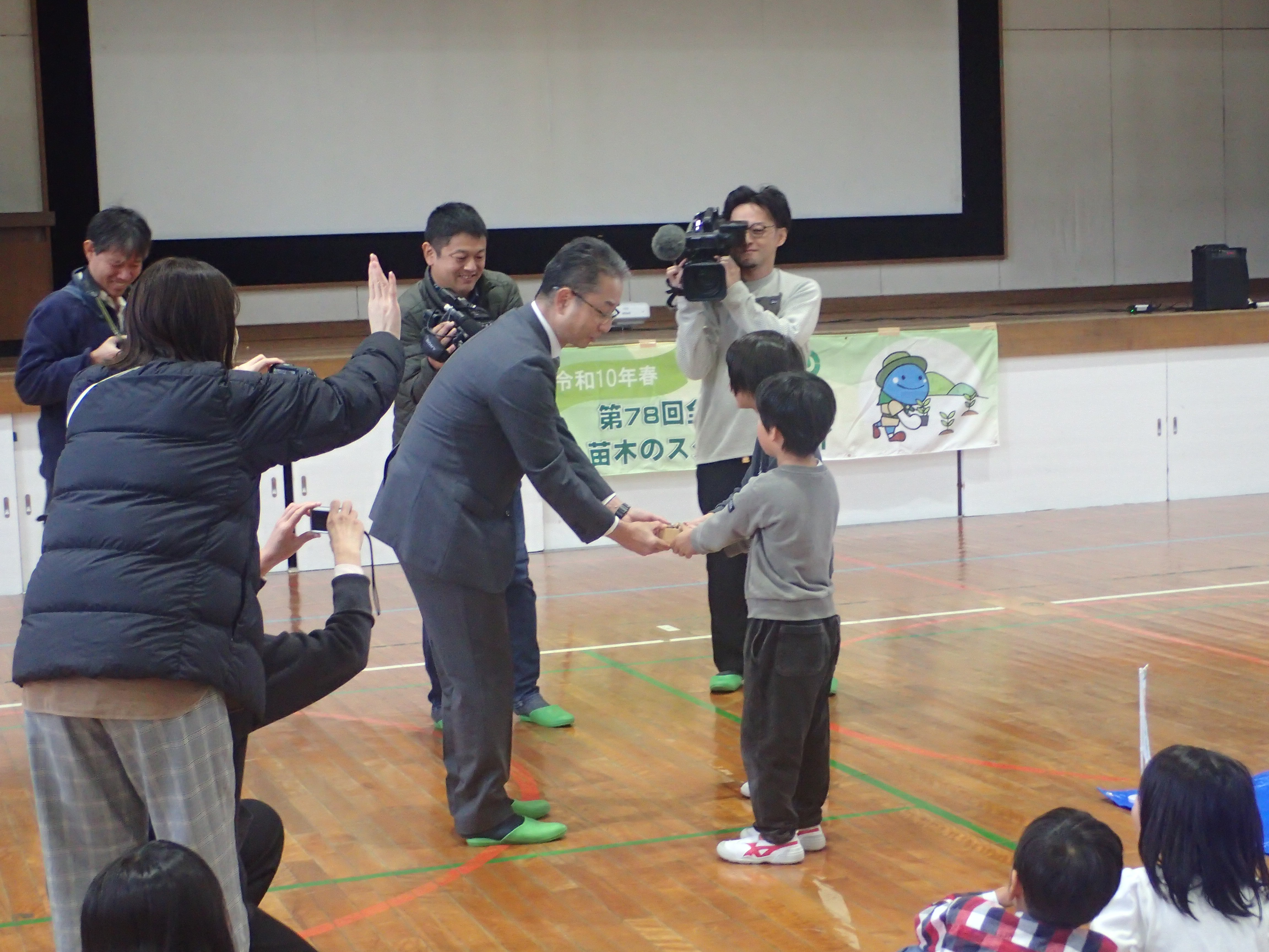 【児童代表にどんぐりの受け渡し】